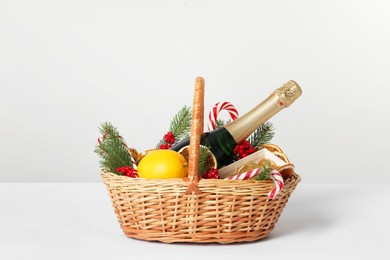 Photo of Wicker gift basket with sparkling wine and Christmas decor isolated on white