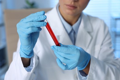 Photo of Laboratory testing. Doctor holding test tube with blood sample indoors, closeup