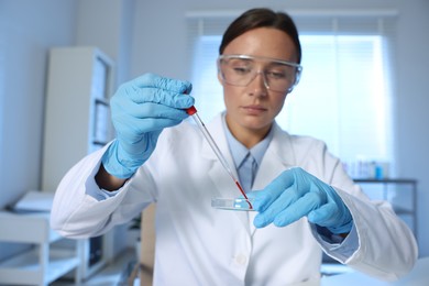 Photo of Laboratory testing. Doctor dripping blood sample into Petri dish indoors, selective focus