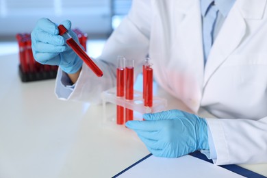 Laboratory testing. Doctor with blood samples at table indoors, closeup