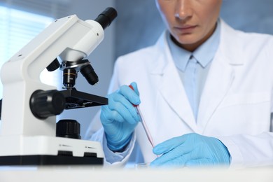 Laboratory testing. Doctor dripping blood sample into Petri dish indoors, closeup