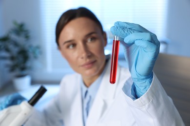 Photo of Laboratory testing. Doctor holding test tube with blood sample indoors, selective focus