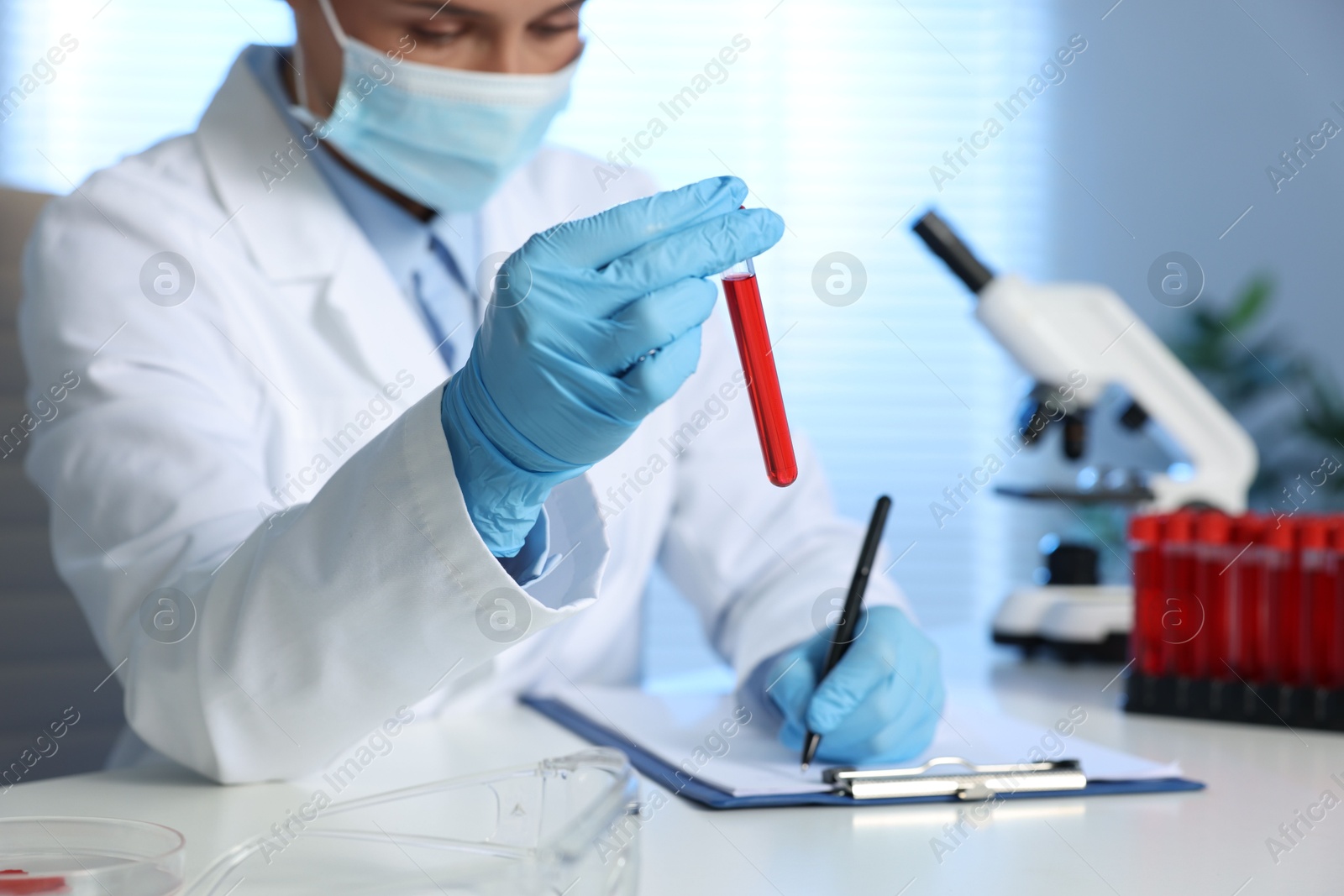 Photo of Laboratory testing. Doctor with blood sample working at table indoors, closeup