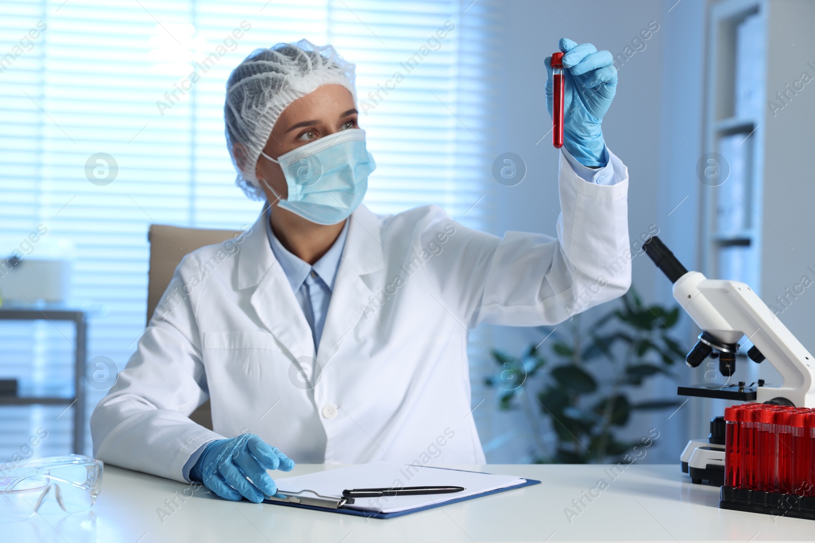 Photo of Laboratory testing. Doctor holding test tube with blood sample at table indoors