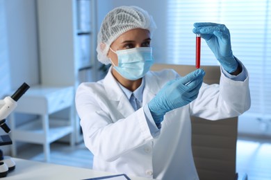 Laboratory testing. Doctor holding test tube with blood sample at table indoors