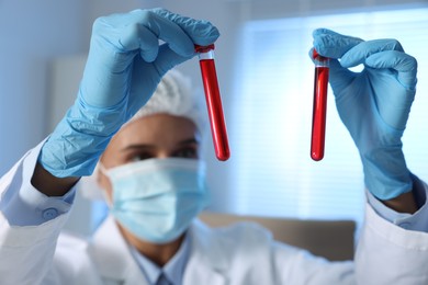 Photo of Laboratory testing. Doctor holding test tubes with blood samples indoors, selective focus