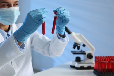 Photo of Laboratory testing. Doctor holding test tubes with blood samples at table indoors