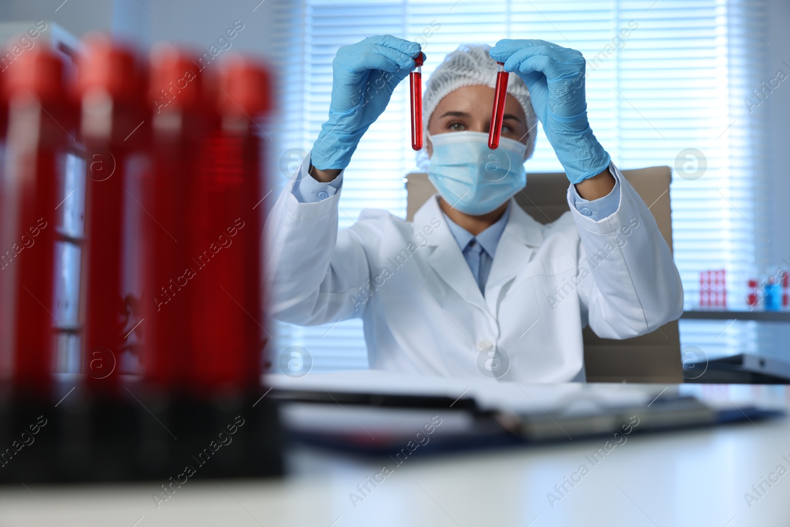 Photo of Laboratory testing. Doctor holding test tubes with blood samples at table indoors