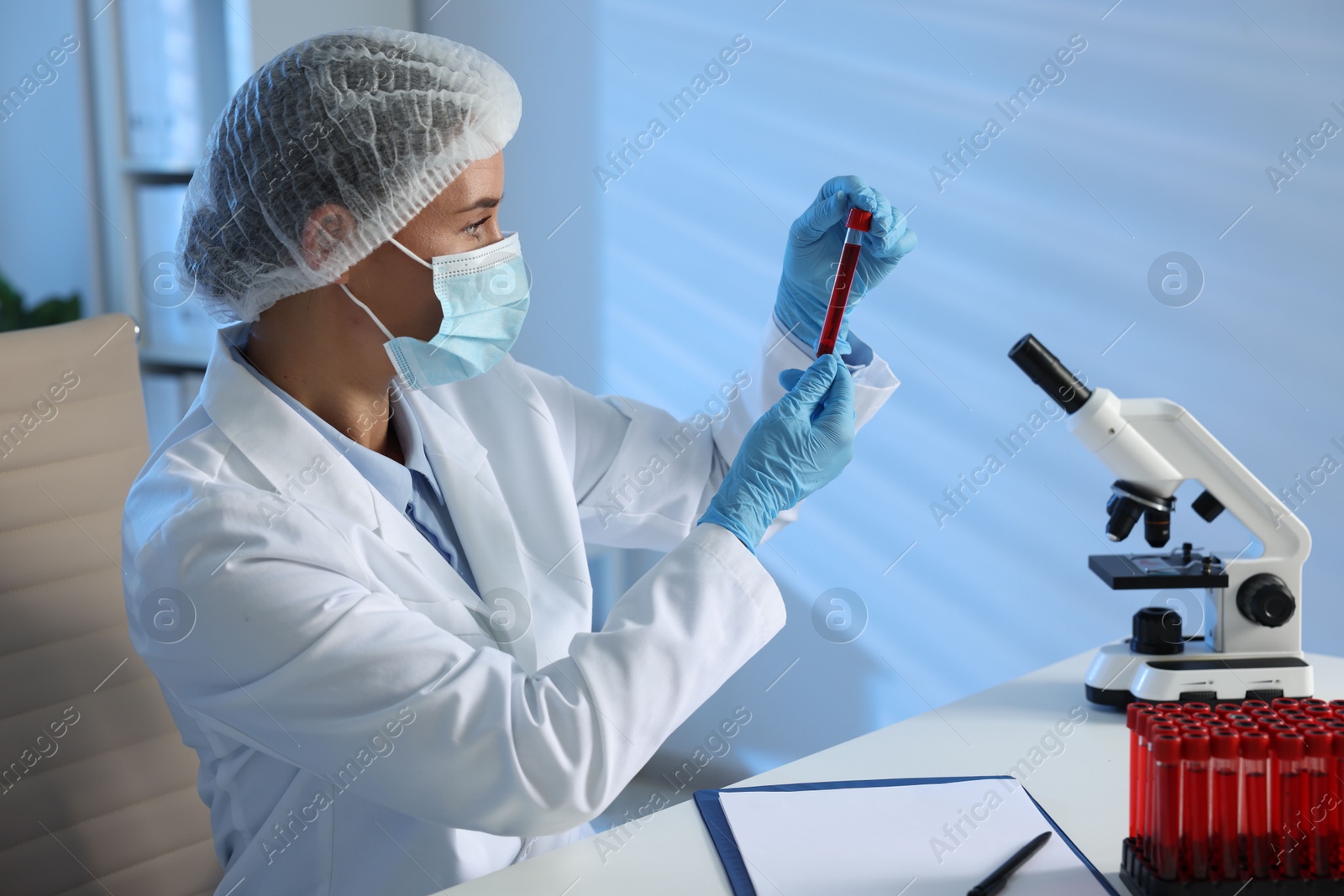 Photo of Laboratory testing. Doctor holding test tube with blood sample at table indoors