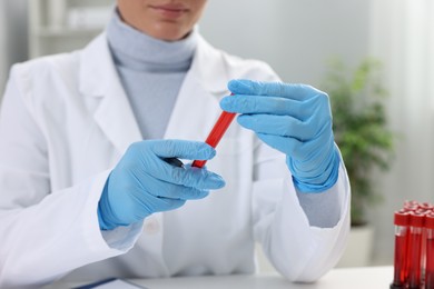 Laboratory testing. Doctor holding test tube with blood sample indoors, closeup