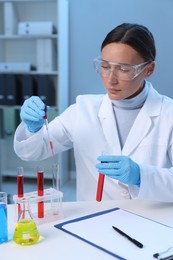 Photo of Laboratory testing. Doctor dripping blood sample into test tube at table indoors