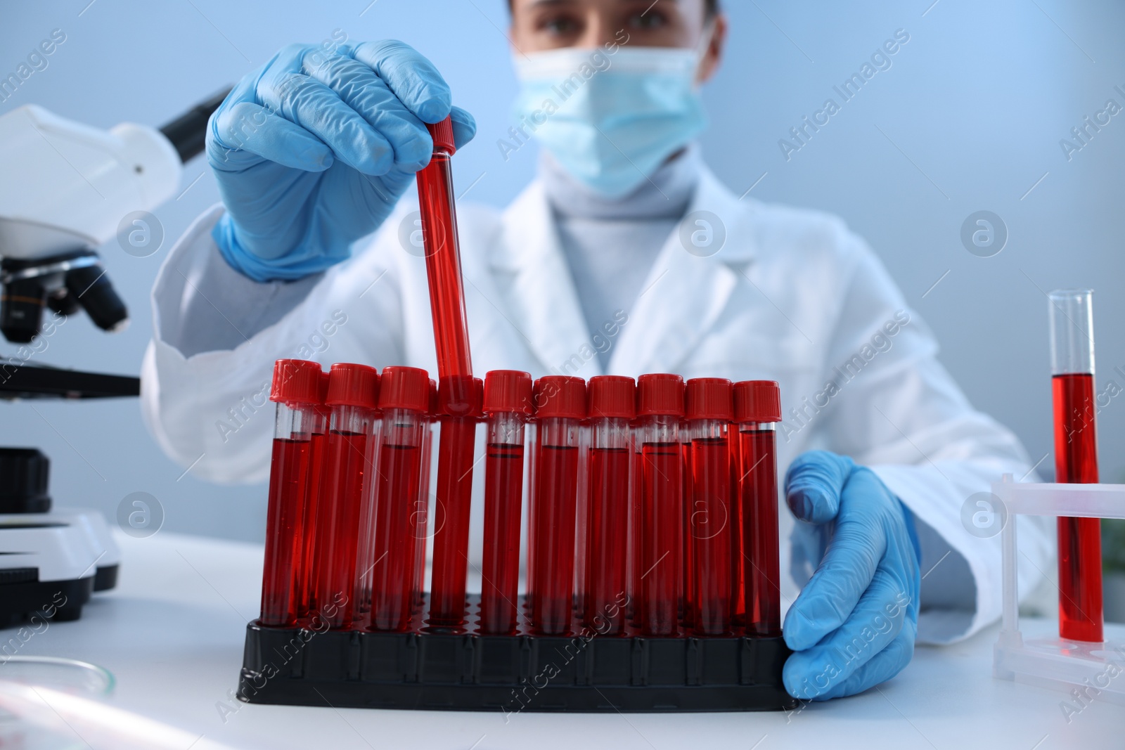 Photo of Laboratory testing. Doctor taking test tube with blood sample at table indoors, selective focus