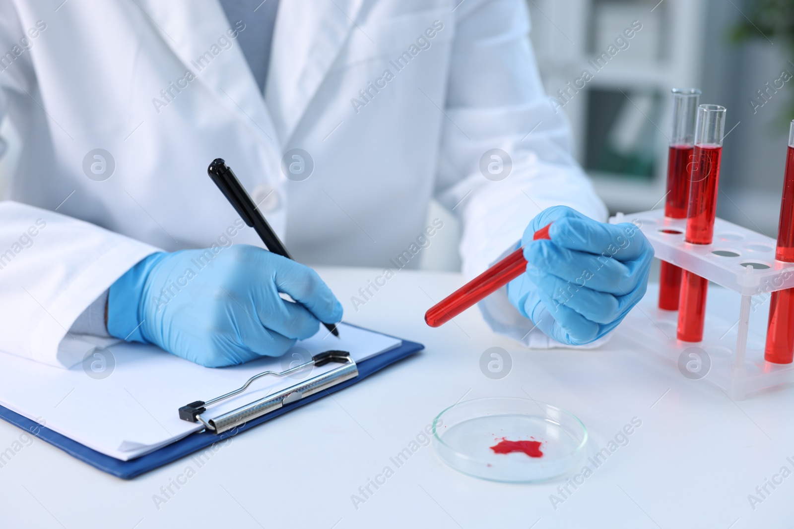 Photo of Laboratory testing. Doctor with blood sample taking notes at table indoors, closeup