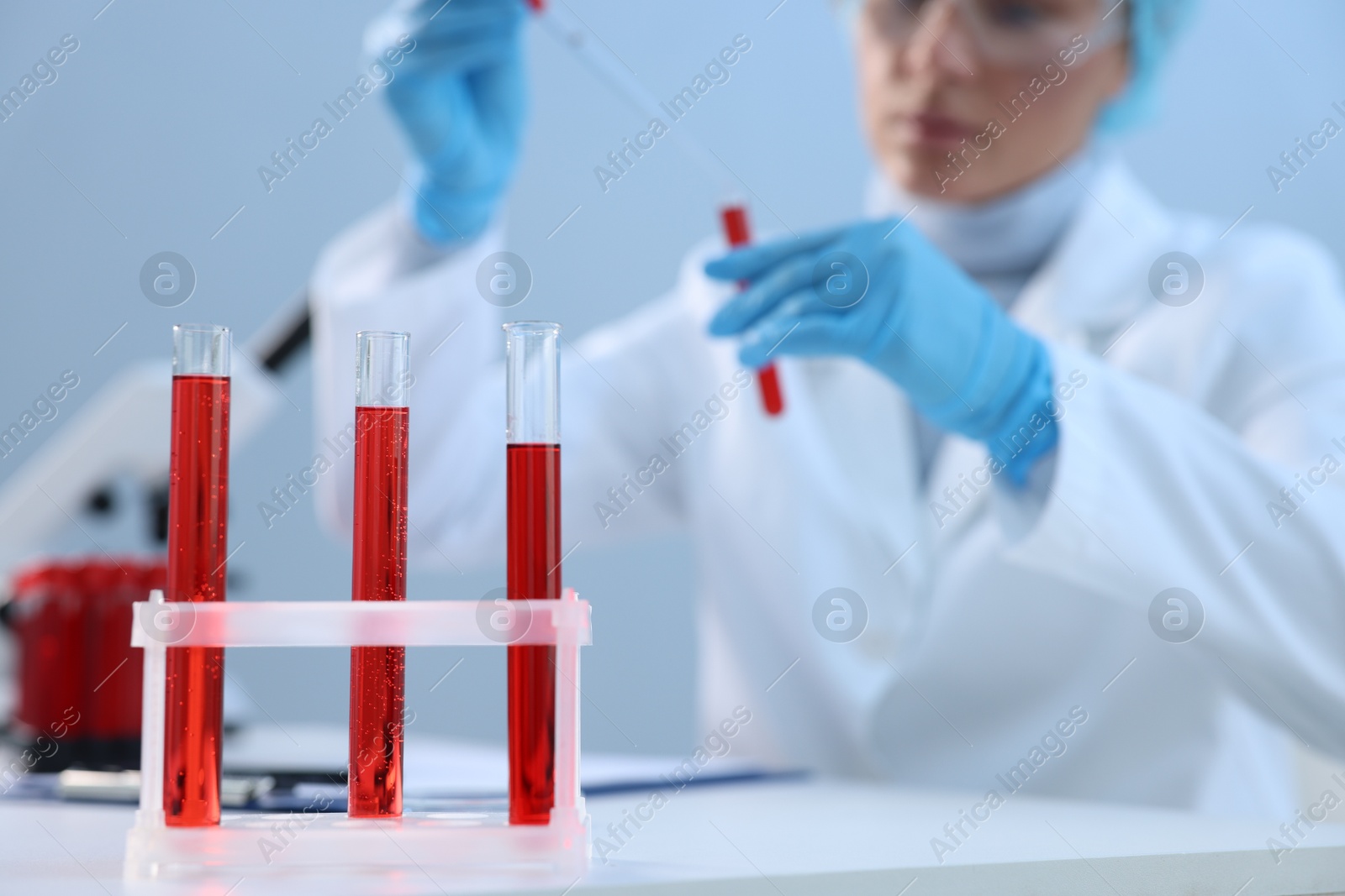 Photo of Laboratory testing. Doctor dripping blood sample into test tube at table indoors, selective focus