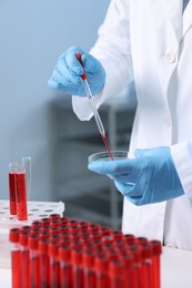 Laboratory testing. Doctor dripping blood sample into Petri dish indoors, closeup