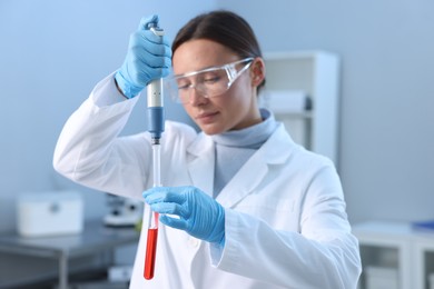 Photo of Laboratory testing. Doctor dripping blood sample into test tube indoors