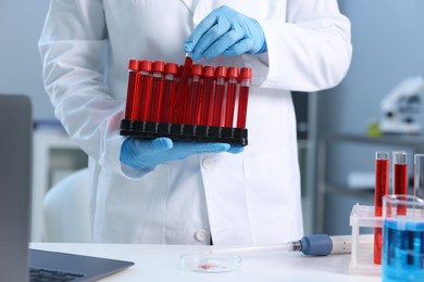 Photo of Laboratory testing. Doctor with blood samples in tubes indoors, closeup