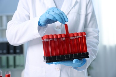 Laboratory testing. Doctor with blood samples in tubes indoors, closeup