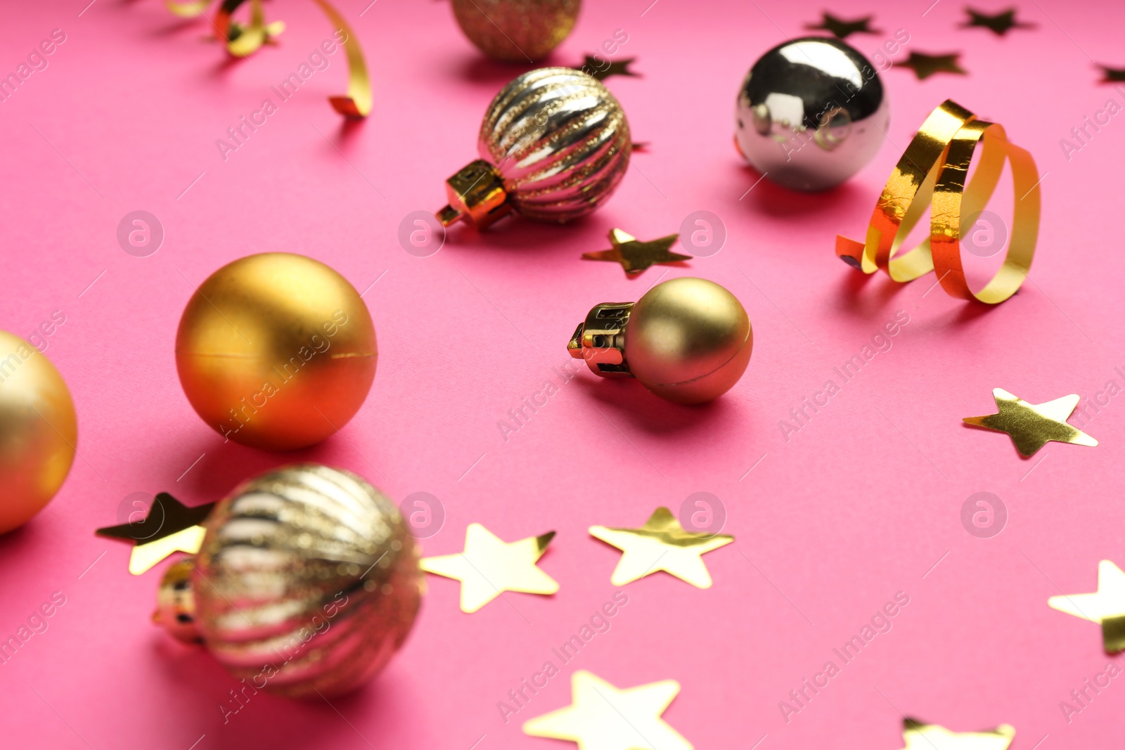 Photo of Confetti and Christmas balls on pink background, closeup