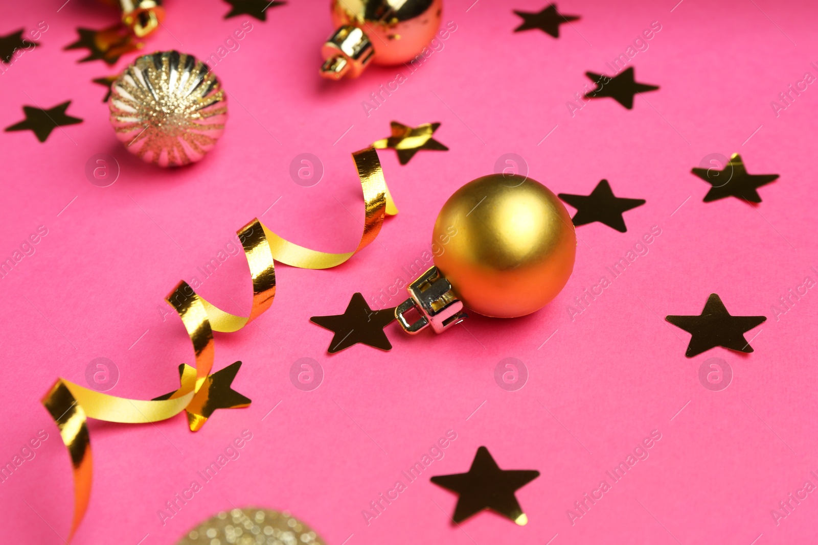 Photo of Confetti and Christmas balls on pink background, closeup