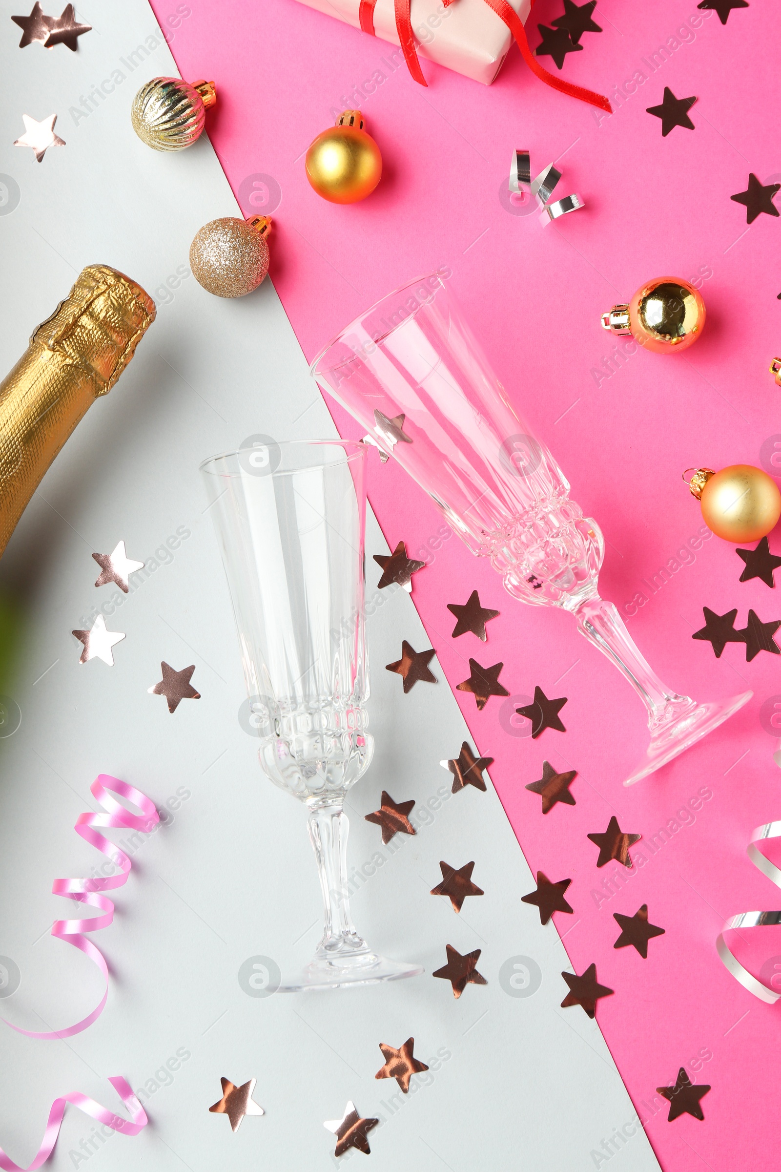 Photo of Flat lay composition with confetti and bottle of sparkling wine on color background. Christmas decor