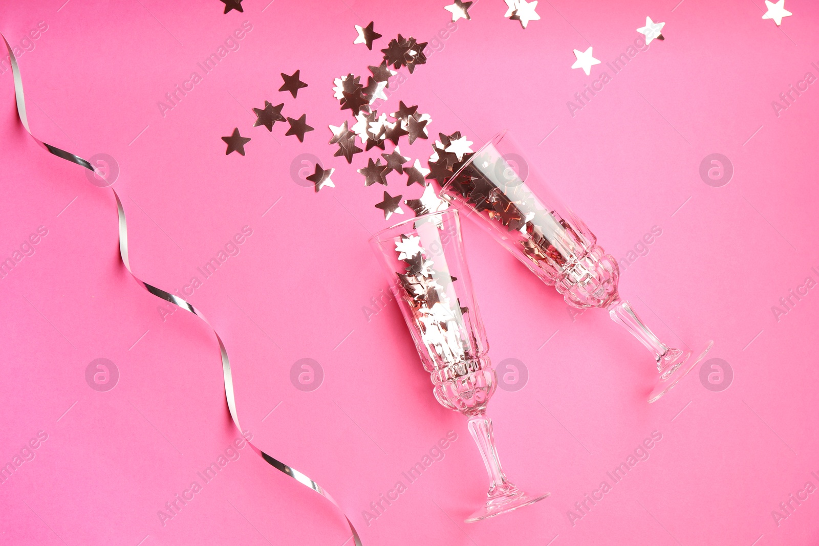 Photo of Wine glasses with confetti on pink background, flat lay. Christmas decor