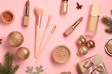 Photo of Different makeup brushes, decorative cosmetics and Christmas decor on pink background, flat lay