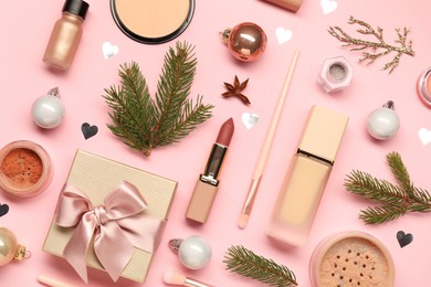 Photo of Different makeup brushes, decorative cosmetics and Christmas decor on pink background, flat lay