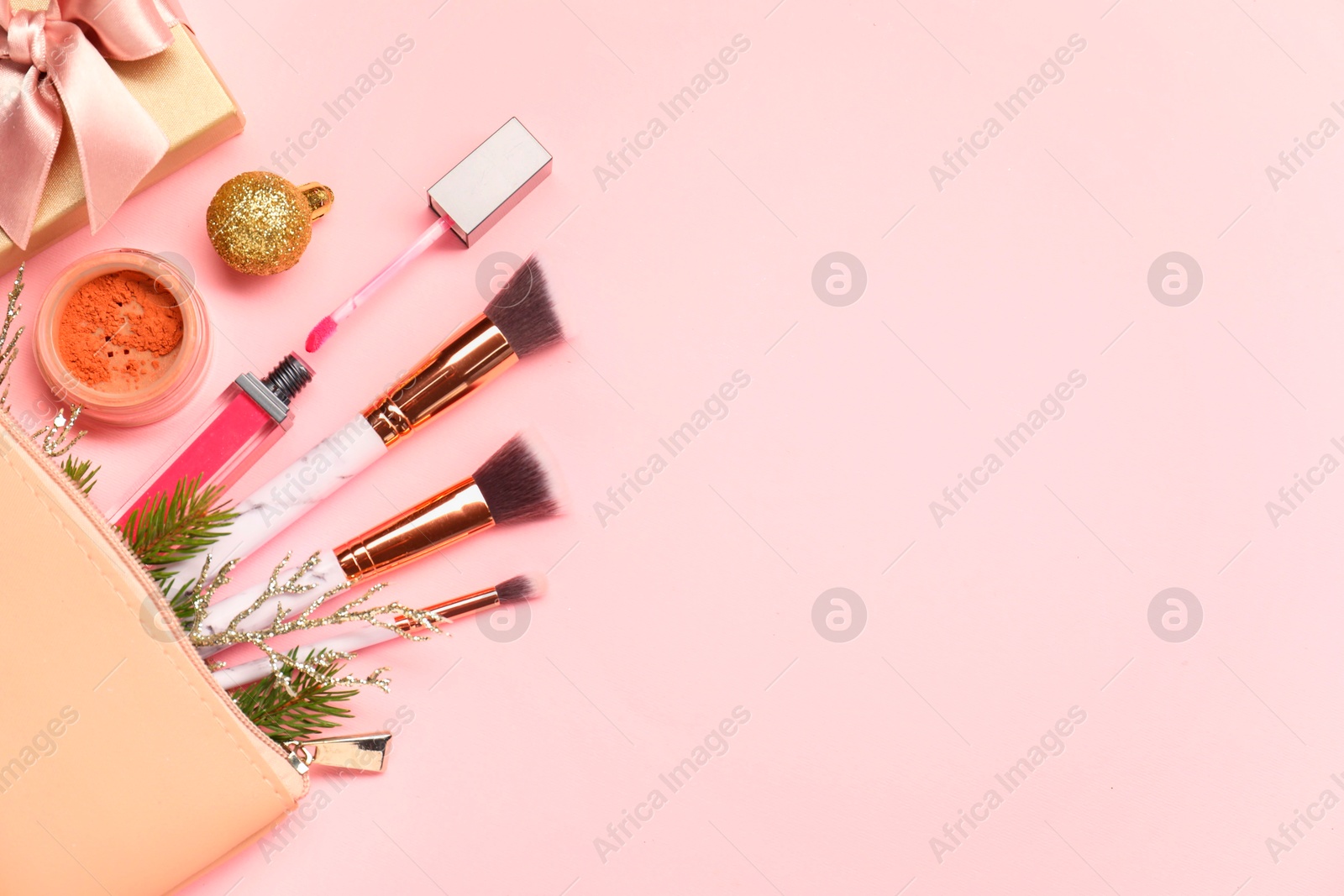 Photo of Different makeup brushes, decorative cosmetics and Christmas decor on pink background, flat lay. Space for text