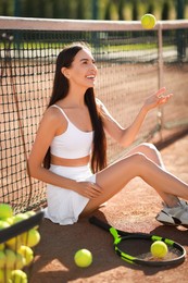 Beautiful woman throwing tennis ball up on court