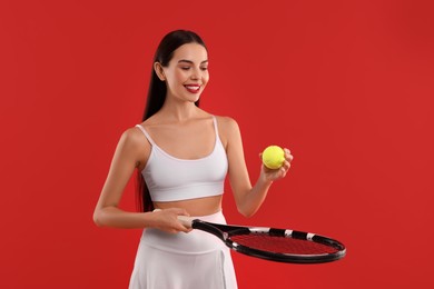 Photo of Happy tennis player with racket and ball on red background