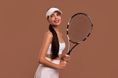 Beautiful young woman with tennis racket on brown background