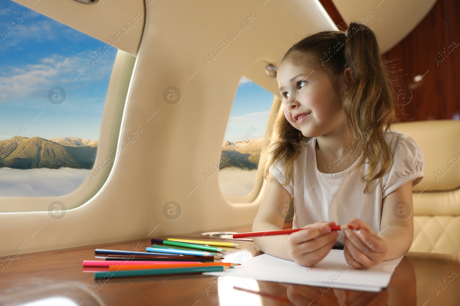 Image of Little girl looking at mountains from airplane window