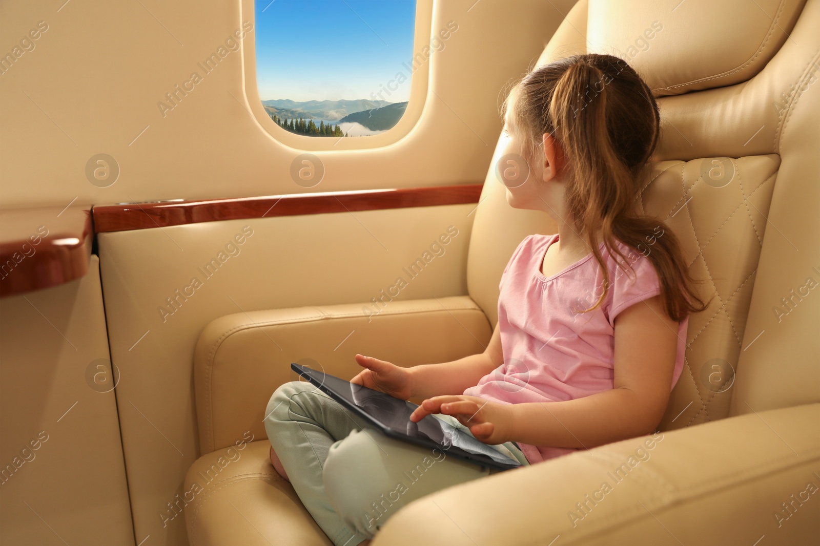 Image of Little girl looking at mountains from airplane window