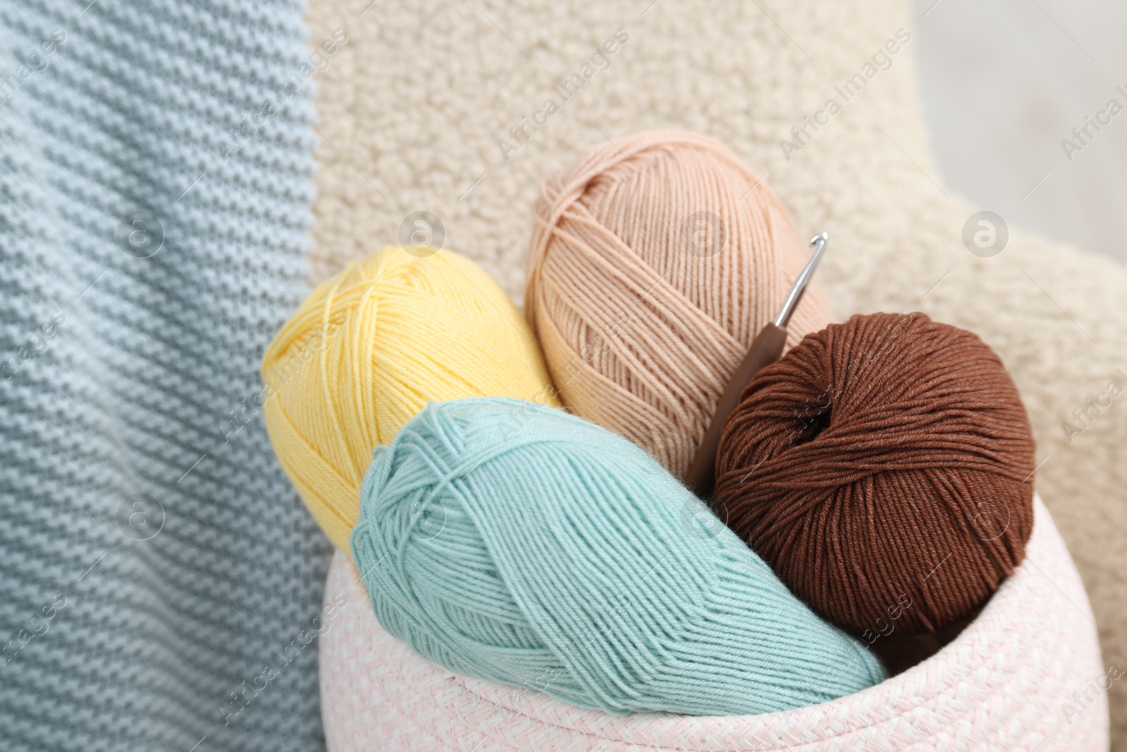 Photo of Knitting material. Skeins of soft yarn and crochet hook on armchair