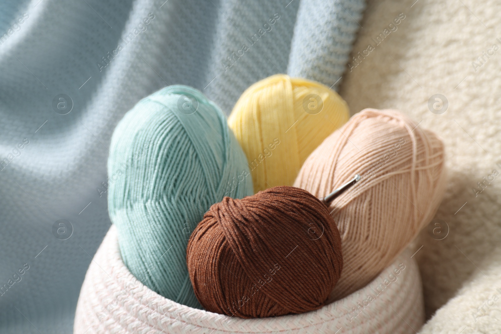 Photo of Knitting material. Skeins of soft yarn and crochet hook on armchair, closeup