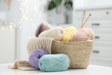 Skeins of yarn, knitting sample and needles on white table indoors