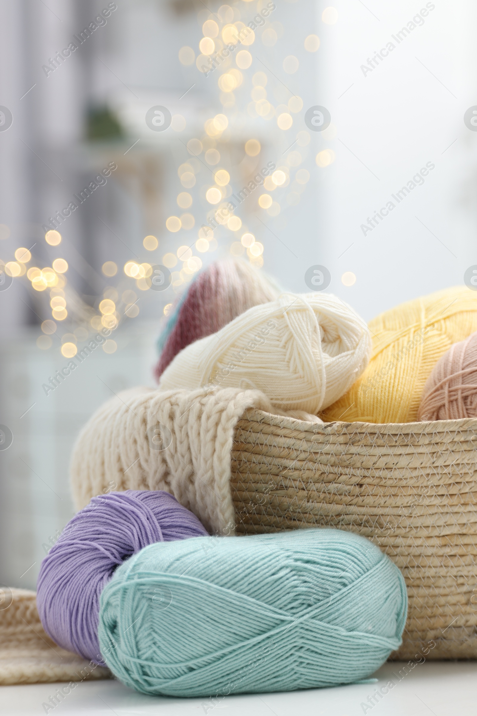 Photo of Skeins of yarn and knitting sample on white table indoors, closeup