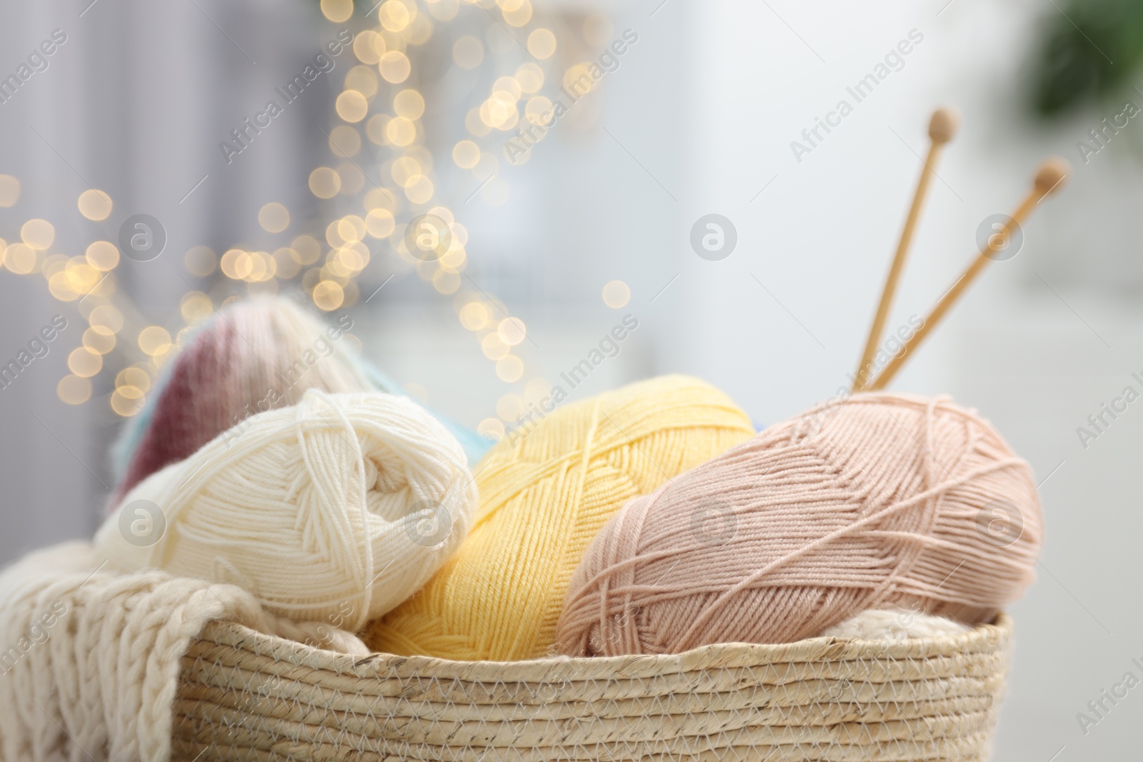 Photo of Skeins of yarn, knitting sample and needles in basket indoors, closeup