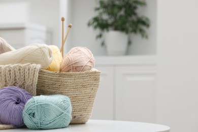 Photo of Skeins of yarn, knitting sample and needles on white table indoors, space for text