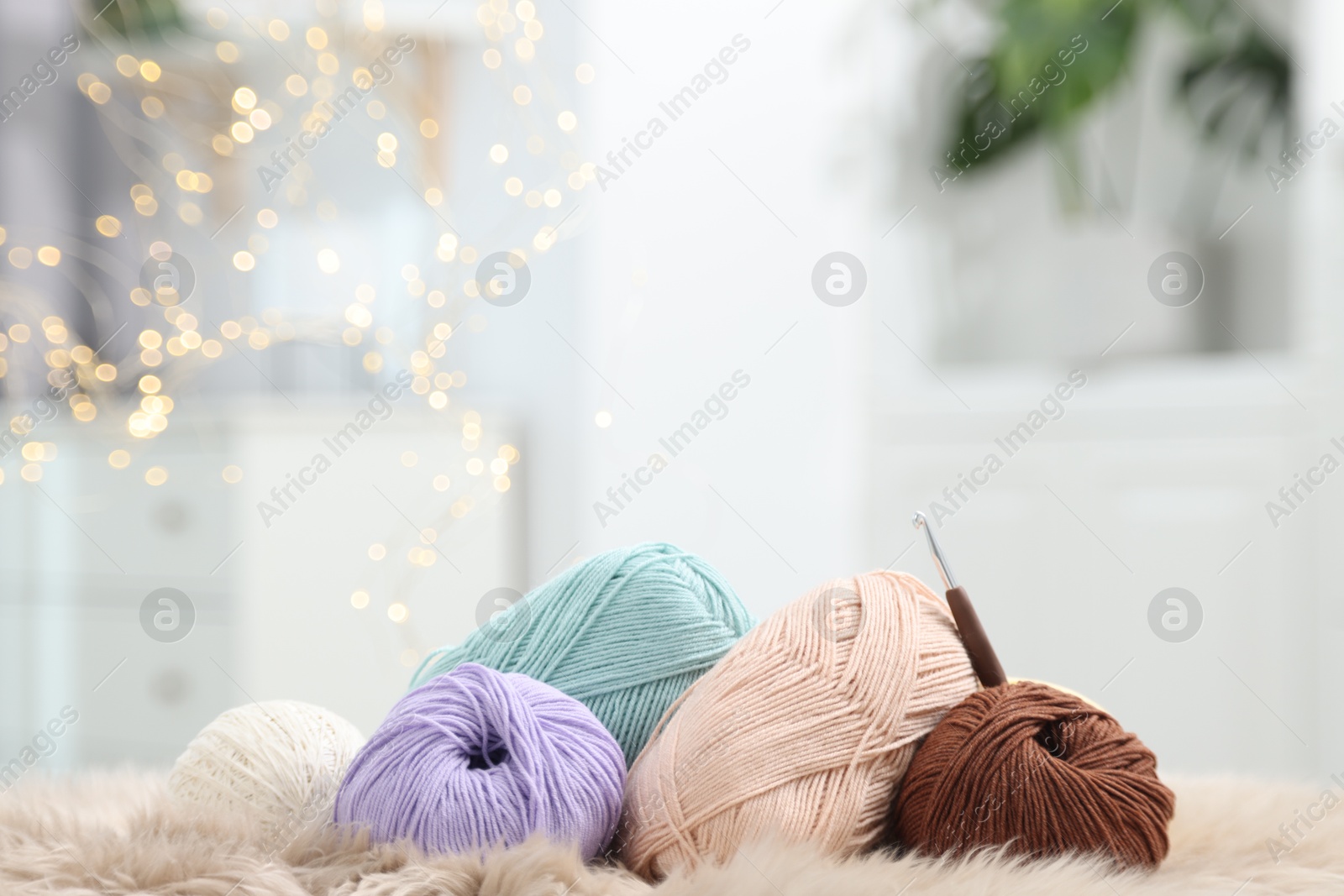 Photo of Knitting material. Skeins of soft yarn and crochet hook on plaid indoors