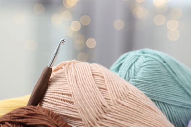 Photo of Knitting material. Skeins of soft yarn and crochet hook indoors, closeup