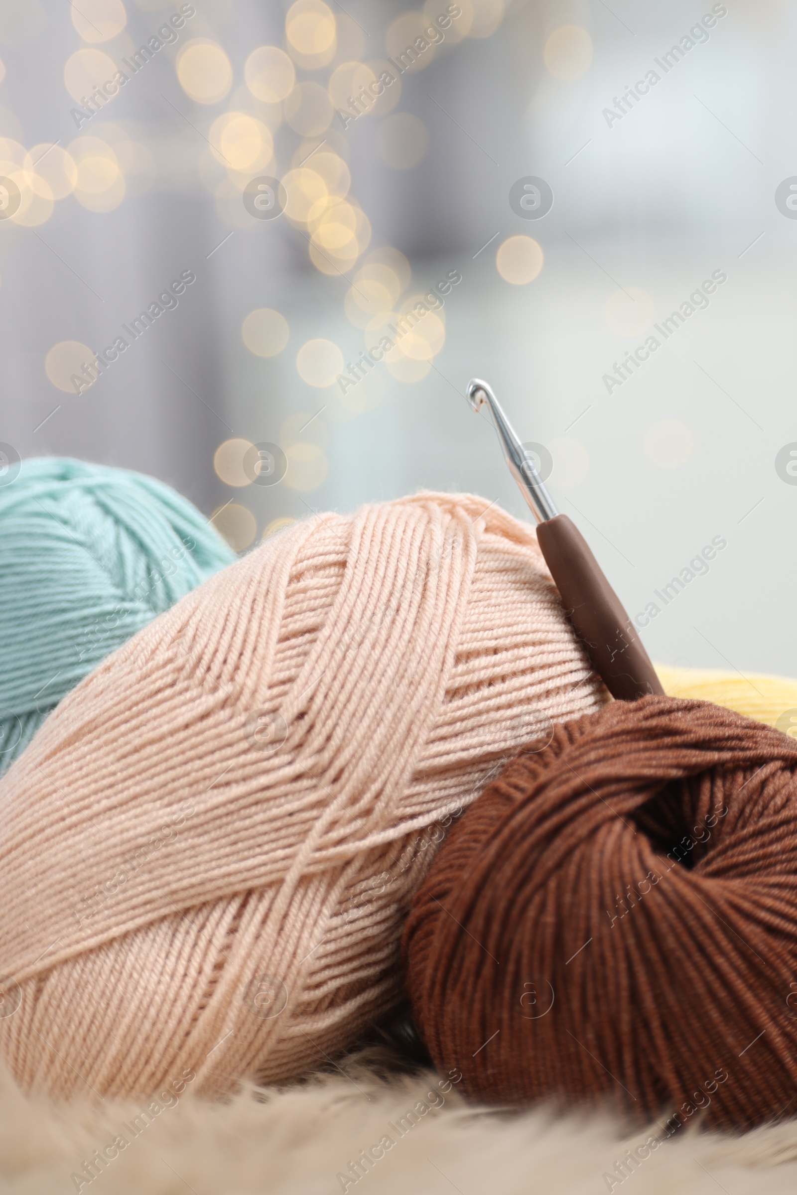 Photo of Knitting material. Skeins of soft yarn and crochet hook on plaid, closeup