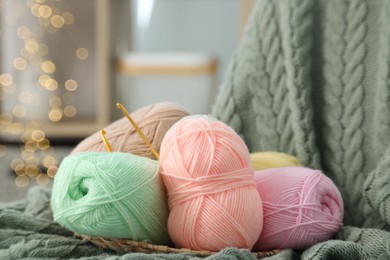 Photo of Knitting material. Skeins of soft yarn and crochet hooks on plaid, closeup