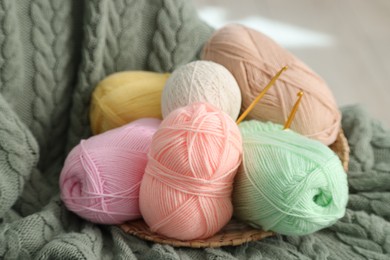 Photo of Knitting material. Skeins of soft yarn and crochet hooks on plaid, closeup