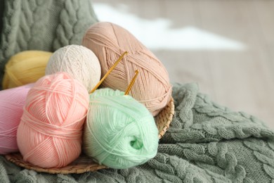 Photo of Knitting material. Skeins of soft yarn and crochet hooks on plaid, space for text