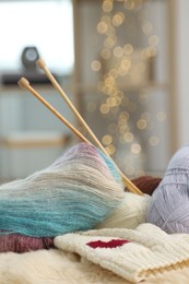 Photo of Skeins of yarn, needles and knitting sample on soft surface indoors, closeup