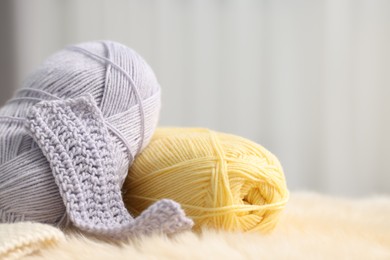 Photo of Skeins of yarn and knitting sample on soft surface indoors, closeup. Space for text