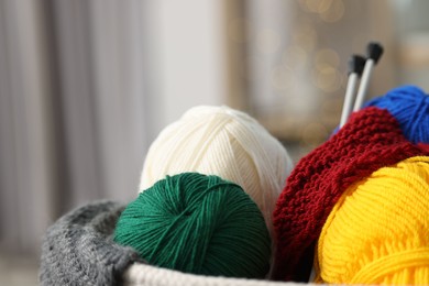 Photo of Skeins of soft yarn, knitting sample and needles indoors, closeup