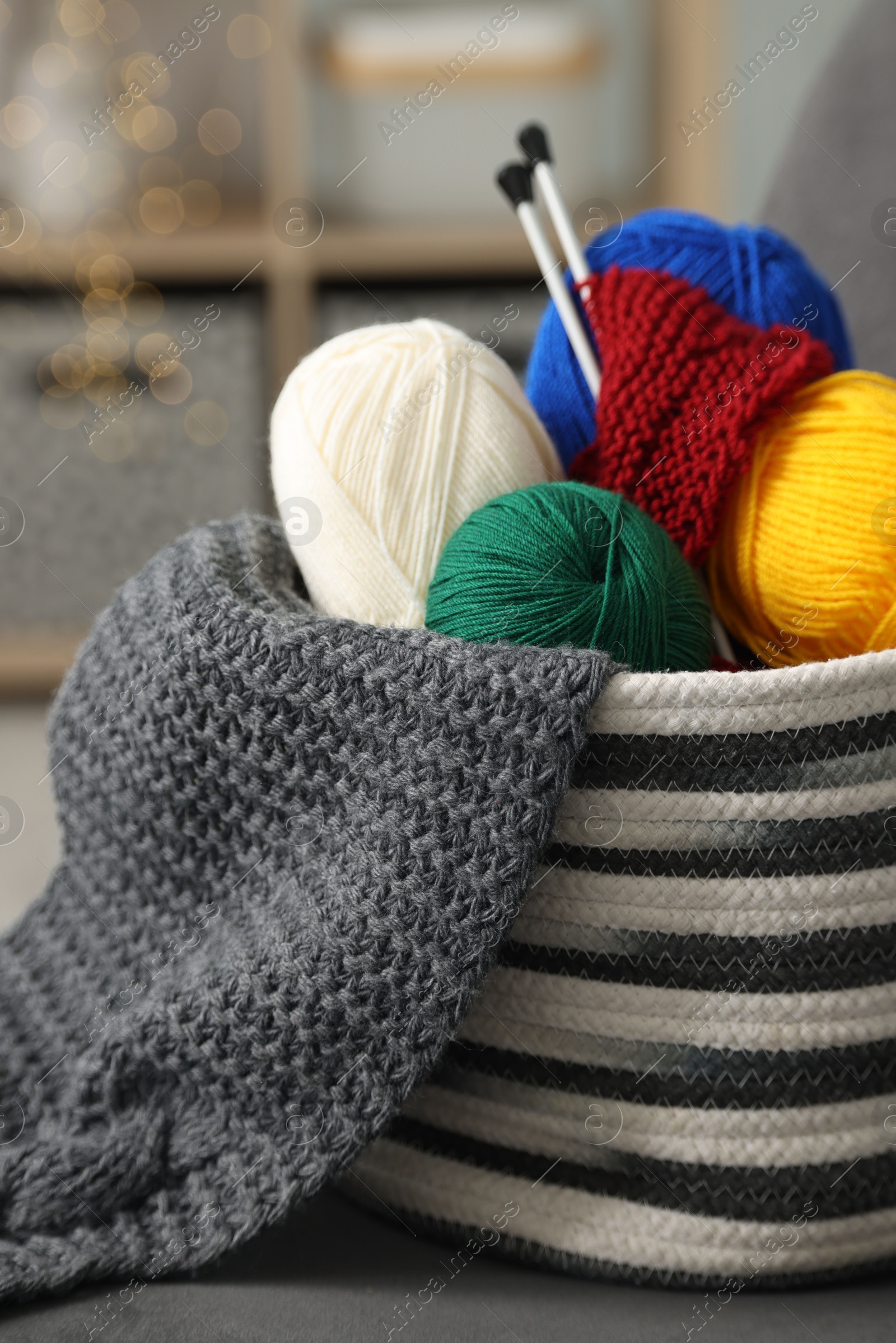 Photo of Skeins of soft yarn, knitting sample and needles on armchair indoors